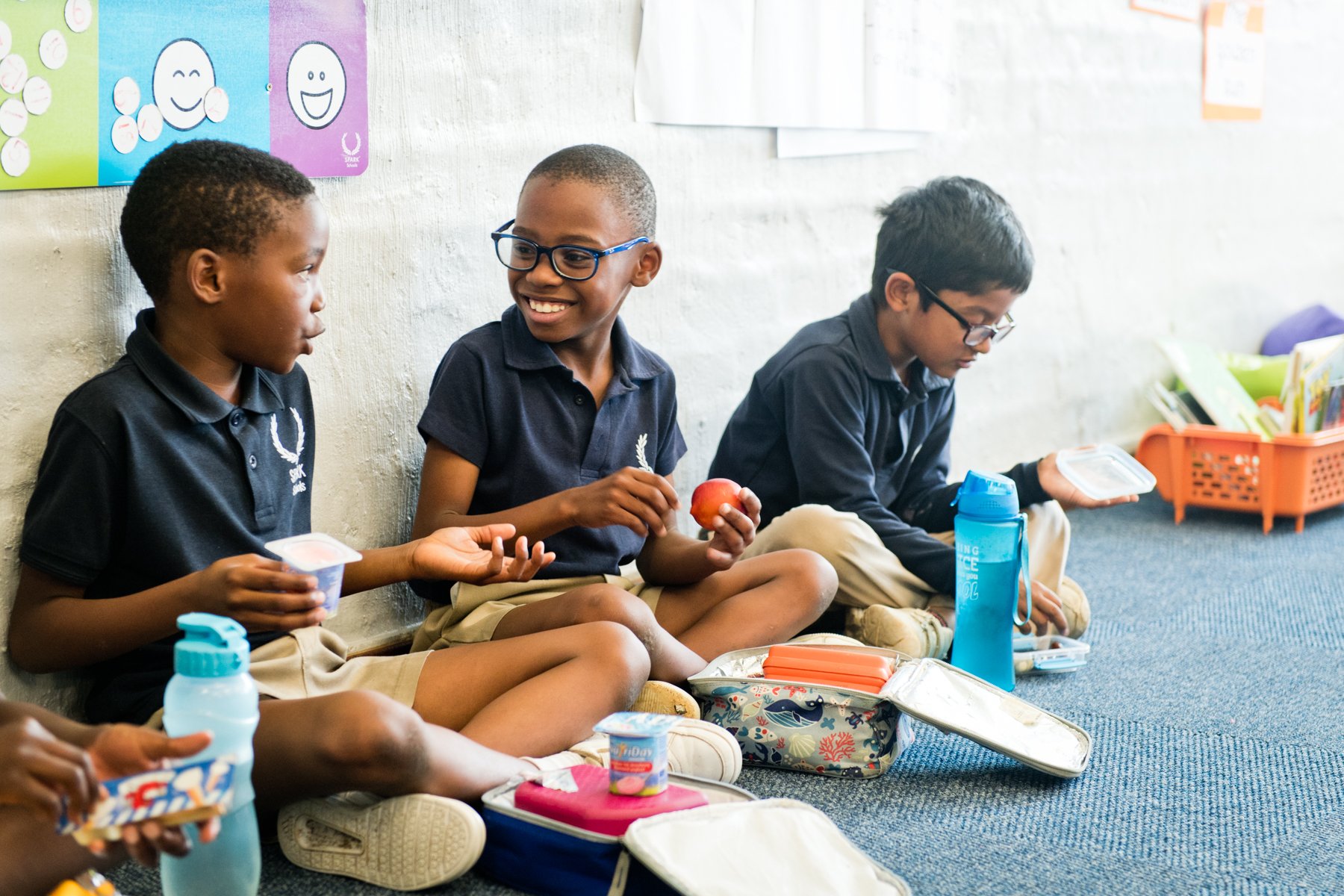 Tre elever på SPARK Schools spiser frokost sammen.